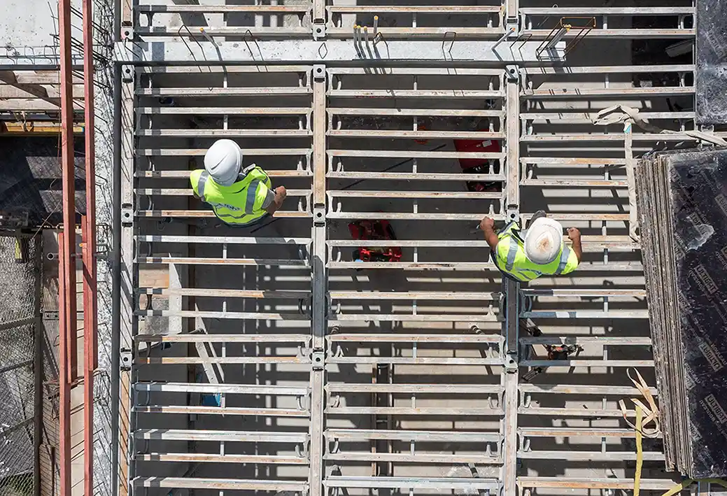 Vue zénithale coffrage chantier BTP Isère — ouvriers armatures béton — Romain Rubini