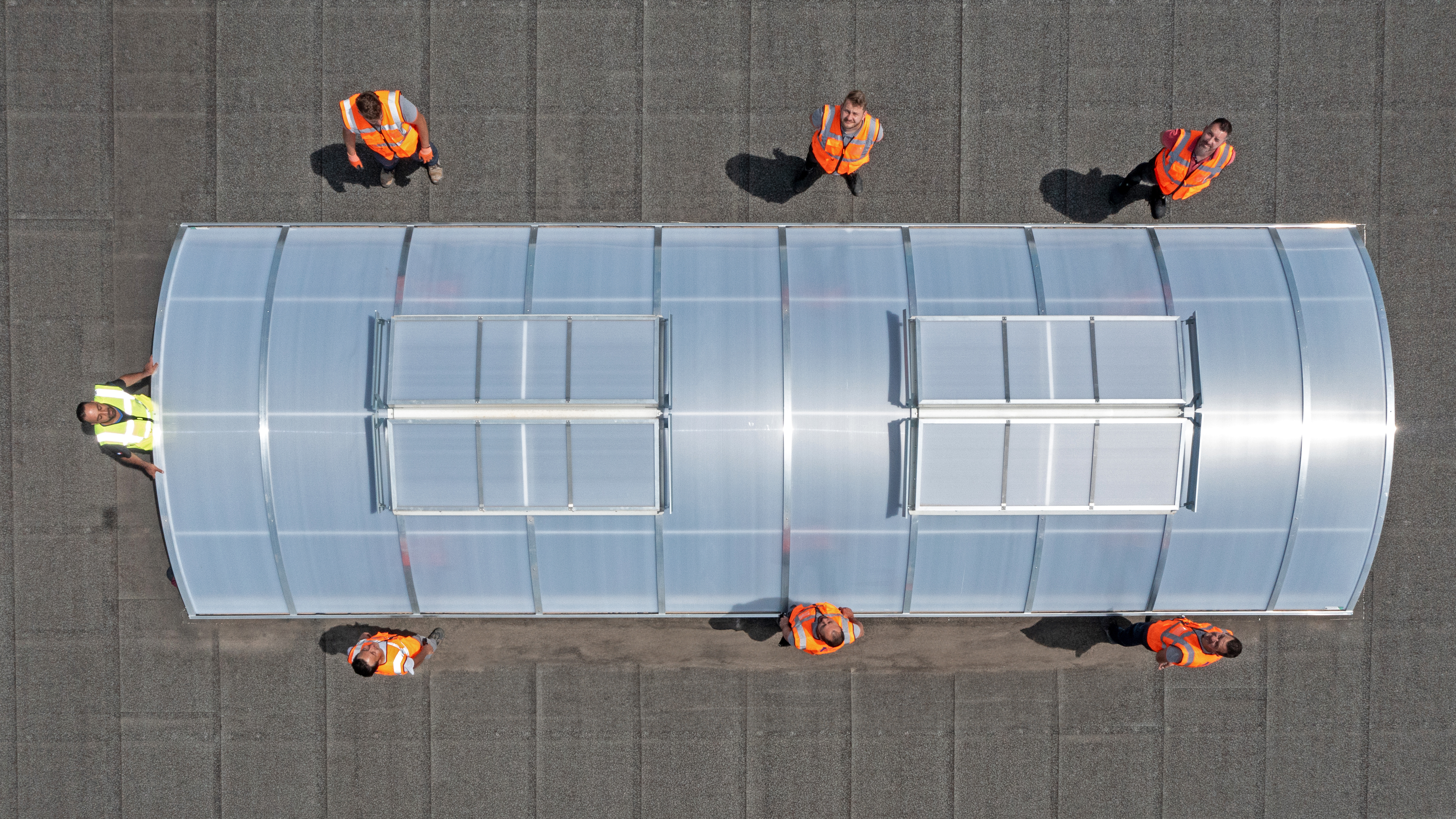 Vue drone d'une équipe BTP en gilets haute visibilité autour d'une verrière de toiture — photographe de chantier Lyon, Romain Rubini